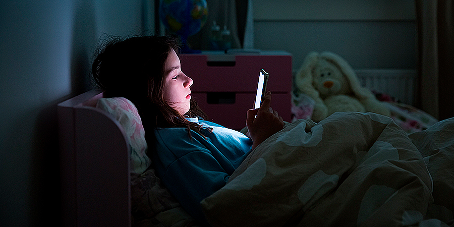 menina deitada no escuro vendo celular 