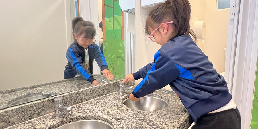 aluna lavando as mãos evitando transmissão de vírus da gripe 