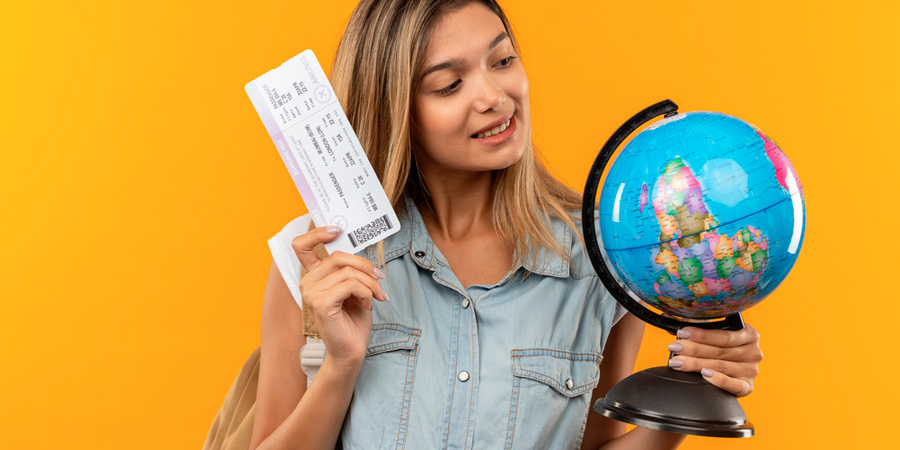 Aluna com mapa mundi em uma mão e a passagem aérea em outra