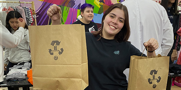 Menina segura sacolas de papel no bazar da escola