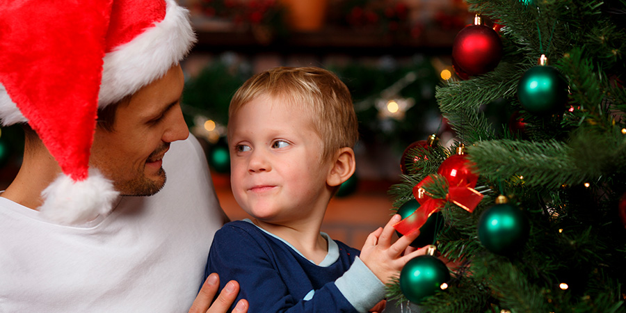 menino encostado na árvore de natal 