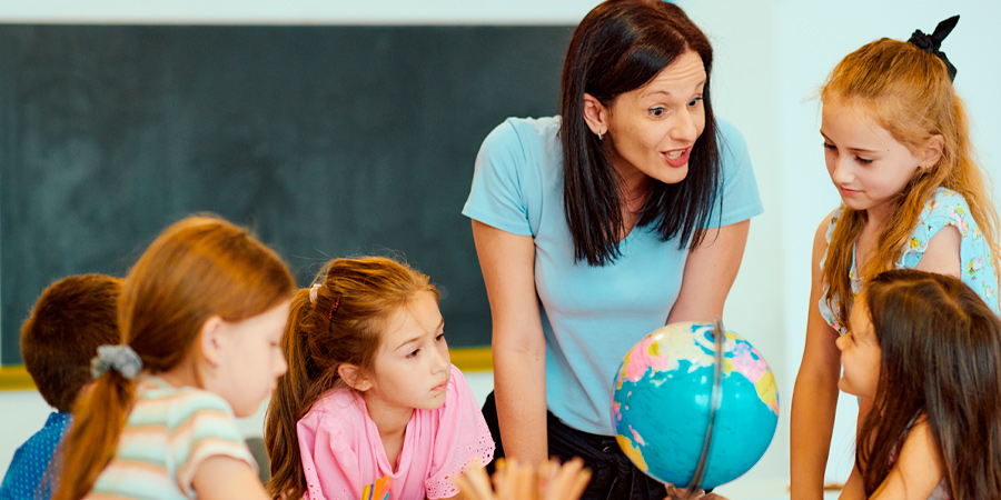 Professora e alunos conversando em volta da mesa durante uma aula